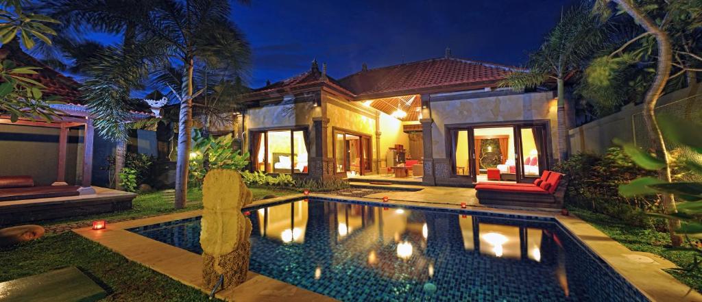 a house with a swimming pool in front of a house at Bali Aroma Exclusive Villas in Seminyak