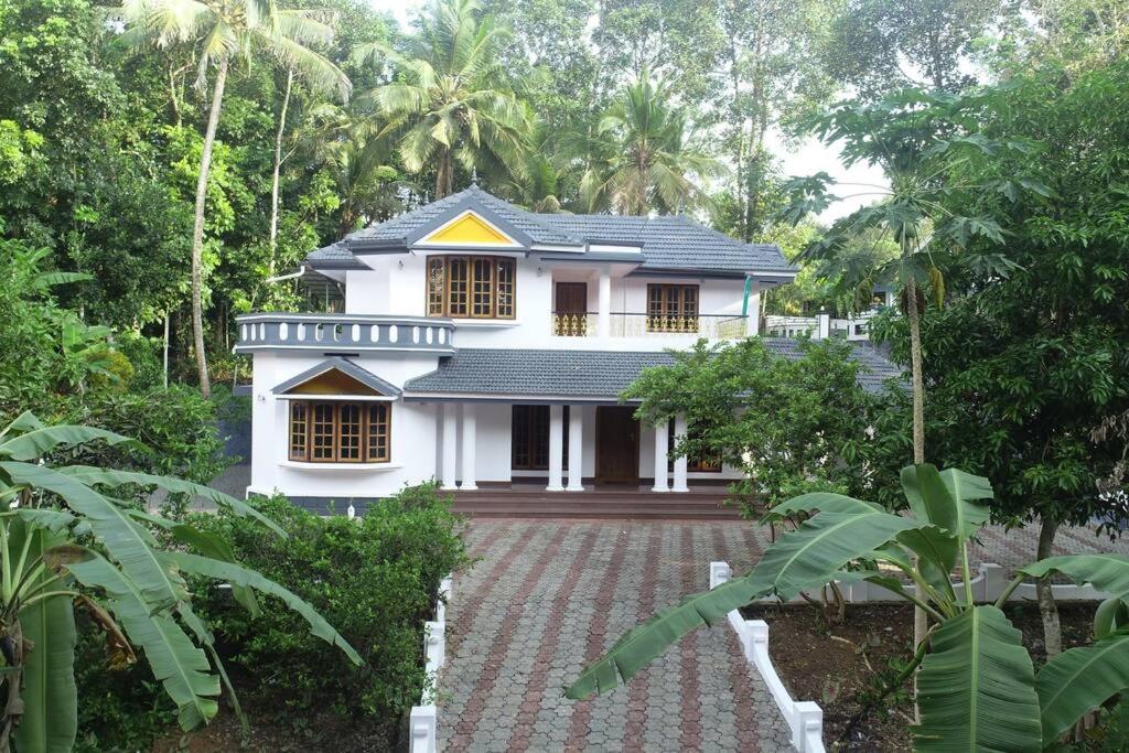une maison blanche au milieu d'une forêt dans l'établissement Holiday homes in kidangoor kottayam kerala, à Kottayam