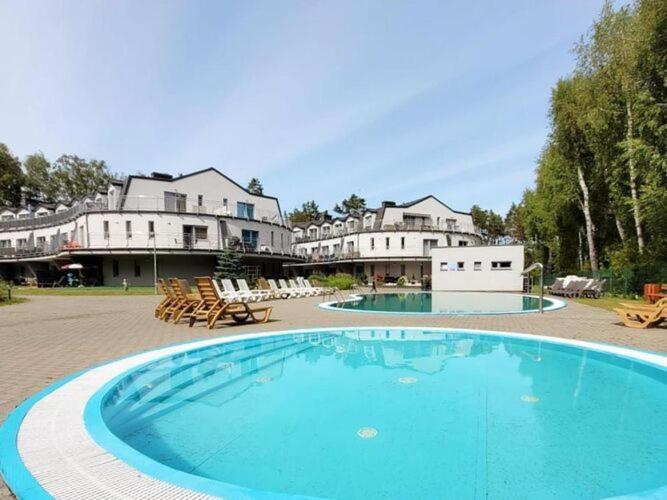 a large blue swimming pool in a yard with buildings at Duplex apartment, 3 bedrooms, pool, Pobierowo in Pobierowo