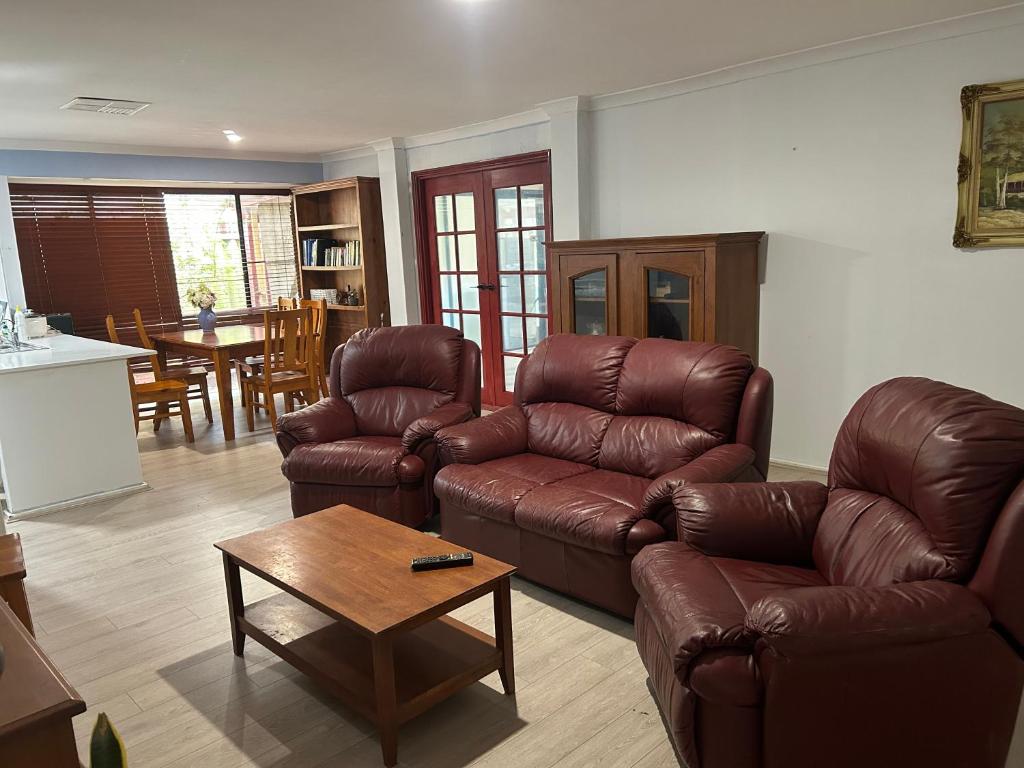 a living room with a leather couch and a table at Single room share bathroom and kitchen in Perth