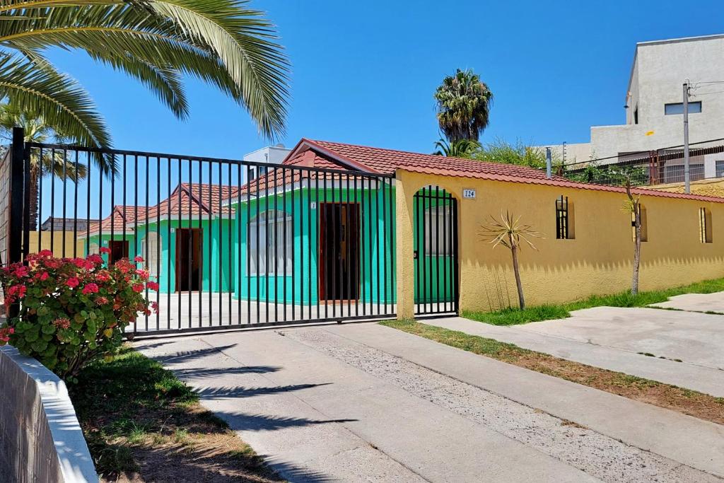 a green and yellow house with a gate at Cabañas Las Flores - Barrio residencial La Herradura in Coquimbo