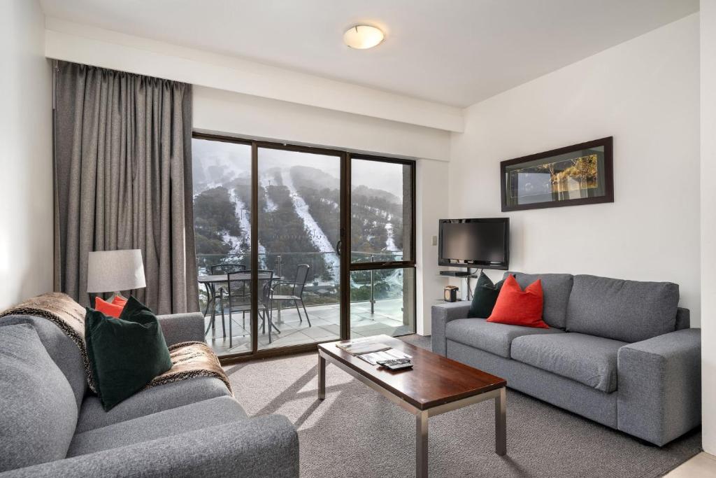 a living room with two couches and a table at Lantern 1 Bedroom Balcony with breathtaking view in Thredbo