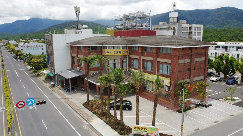 un bâtiment sur le côté d'une rue bordée de palmiers dans l'établissement 池上大地飯店, à Chishang