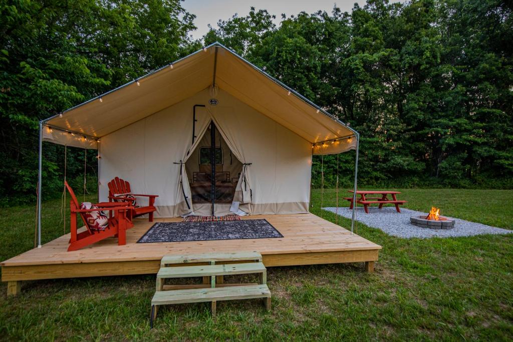a tent with a table and chairs in a field at Roaring River Luxury Glamping #4 in Cassville