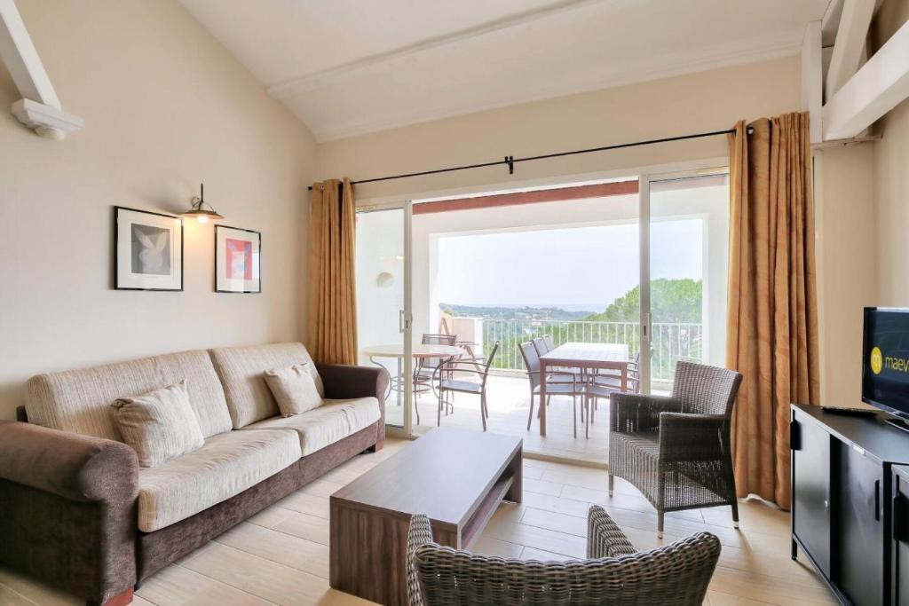 ein Wohnzimmer mit einem Sofa und einem Tisch mit Stühlen in der Unterkunft Les Bastides aux Restanques du Golfe de St Tropez - Maeva Home - Bastide spac 59 in Grimaud