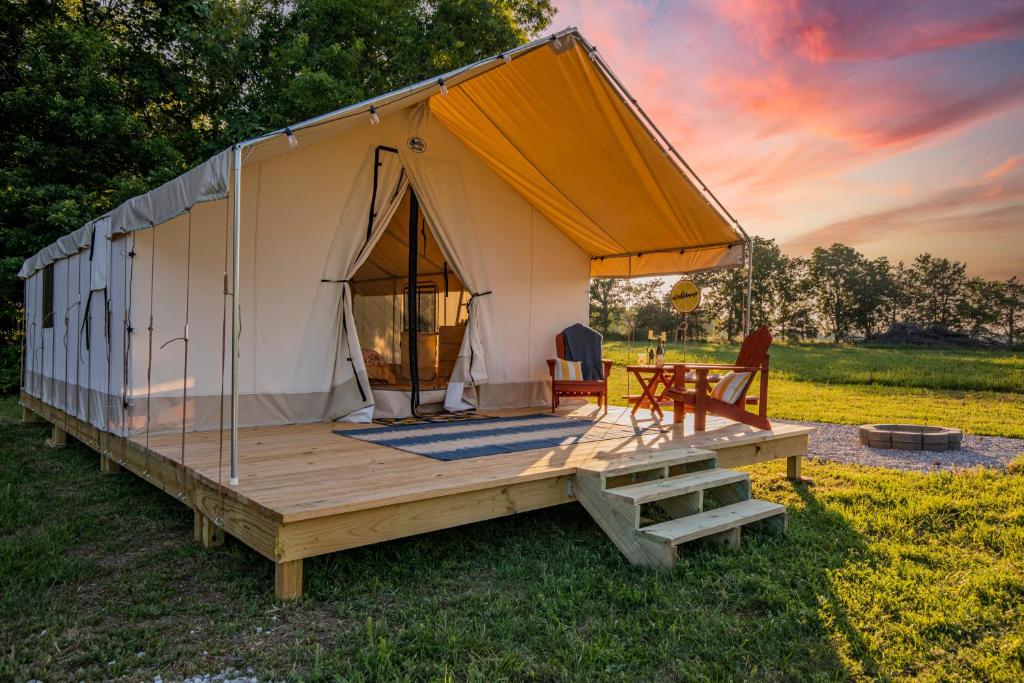 a tent with a wooden deck and a table at Glamping at Roaring River - Queen Tent in Cassville