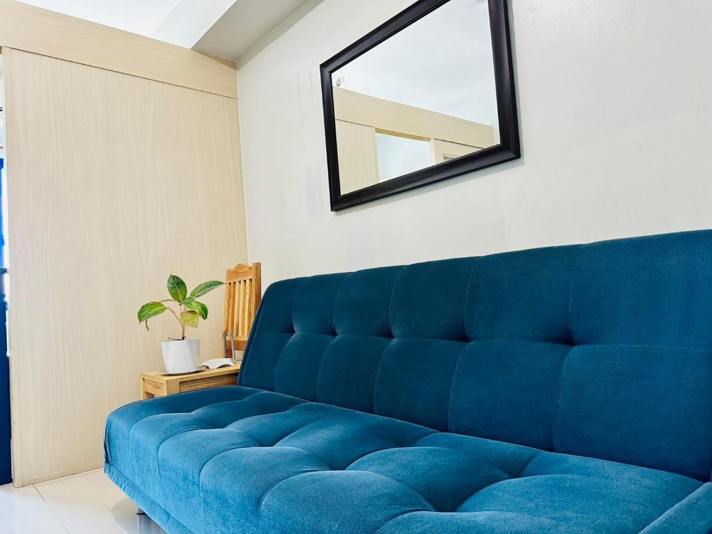 a blue couch in a room with a mirror at Sea Residences - Property Val Alano 0995-448-8872 in Manila