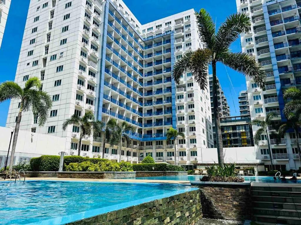 a large building with palm trees and a swimming pool at Sea Residences - Property Val Alano 0995-448-8872 in Manila