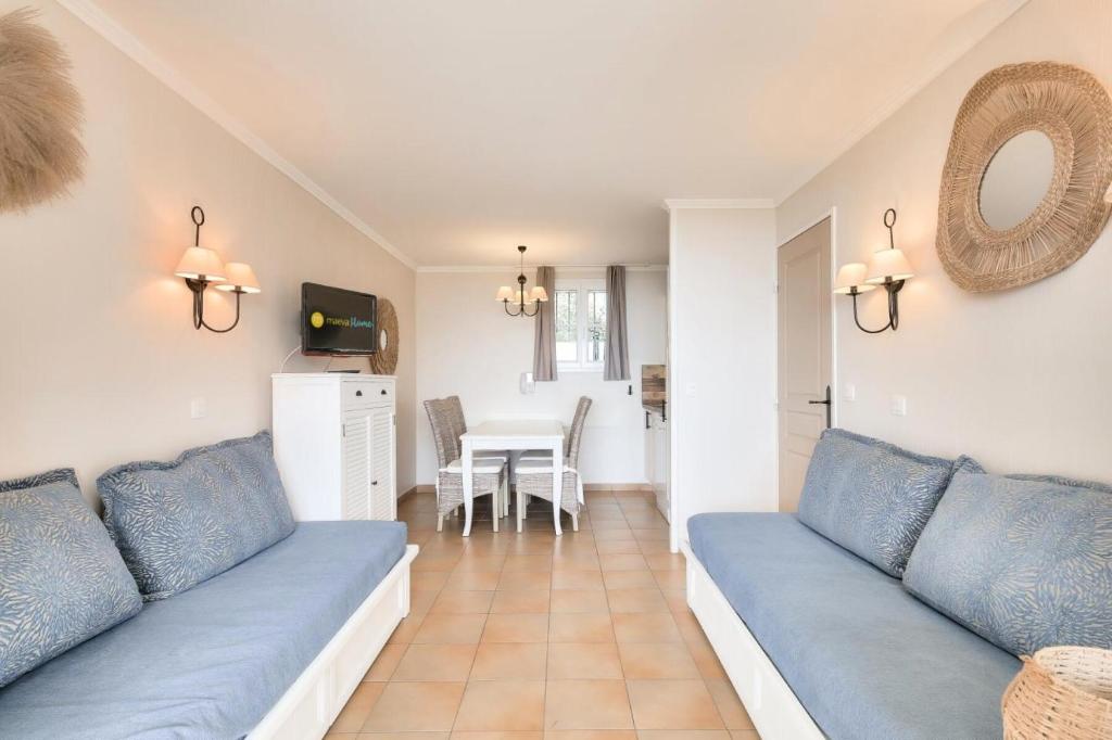 un salon avec un canapé bleu et une table dans l'établissement Les Appartements aux Restanques du Golfe de St Tropez - maeva Home - Appartement 3 pièces 6 personnes - Sélection - vue Mer MAE-0514, à Grimaud