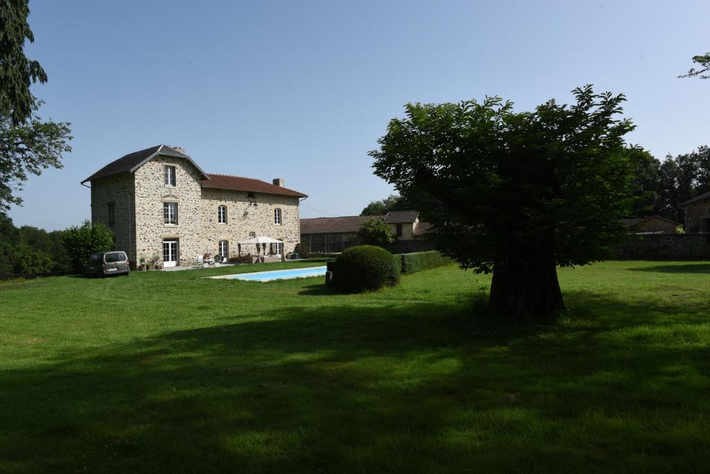 a large stone house with a tree in the yard at Chambres d'hôtes La Babinerie in Saint-Léonard-de-Noblat
