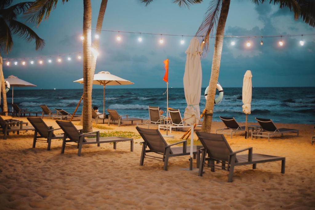 een groep stoelen en parasols op het strand bij Amorii Hotel in Phu Quoc