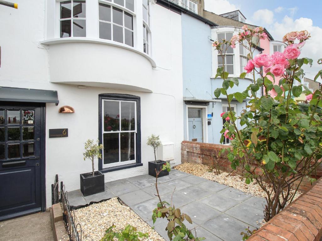 uma casa branca com uma porta preta e flores em 6 The Terrace em Weymouth