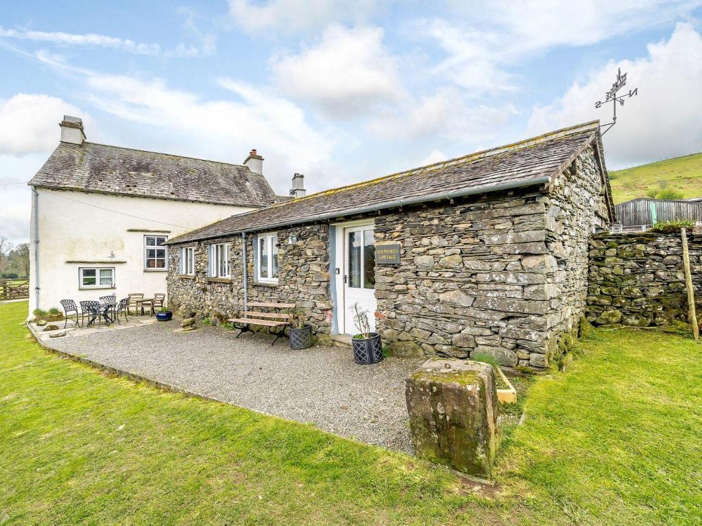 an old stone house with a grassy yard at Shepherds Cottage in Ambleside