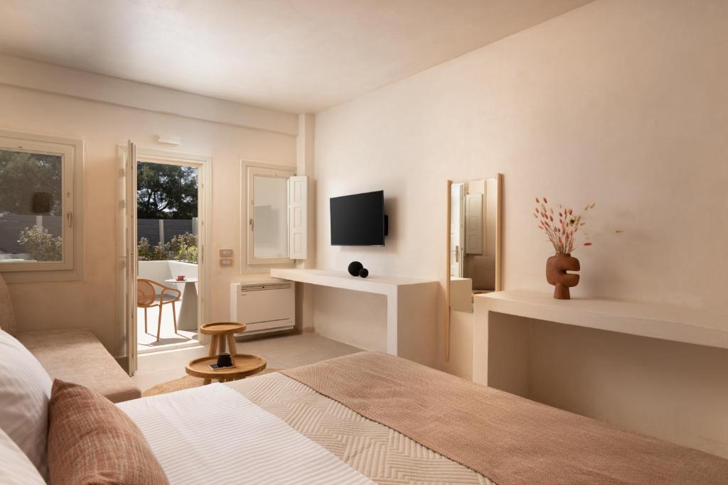 a white bedroom with a bed and a tv at Acanthus Oia - Suites With Private Hot Tub in Oia