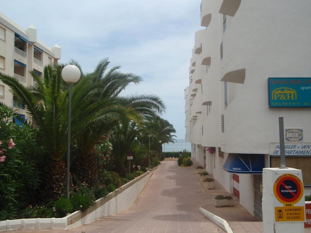 an empty street next to a building with palm trees at Margaritas in Alcossebre
