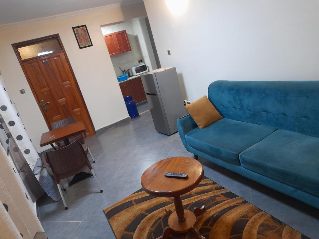 a living room with a blue couch and a table at Ella Apartment Namirembe Road in Kampala