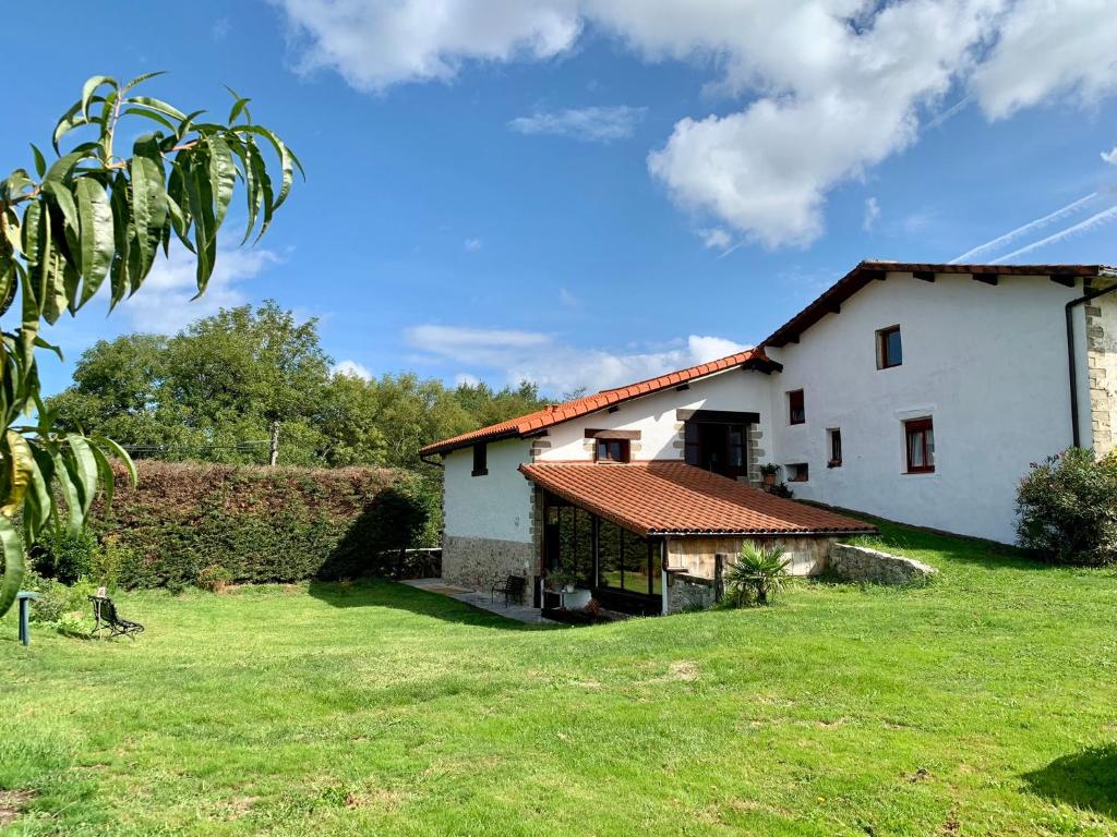 a large white house with a green yard at Bidegurutzeta landetxea in Urnieta