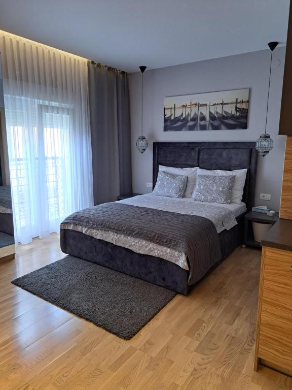 a bedroom with a large bed and a wooden floor at Apartmani Kameno Sidro in Bilice