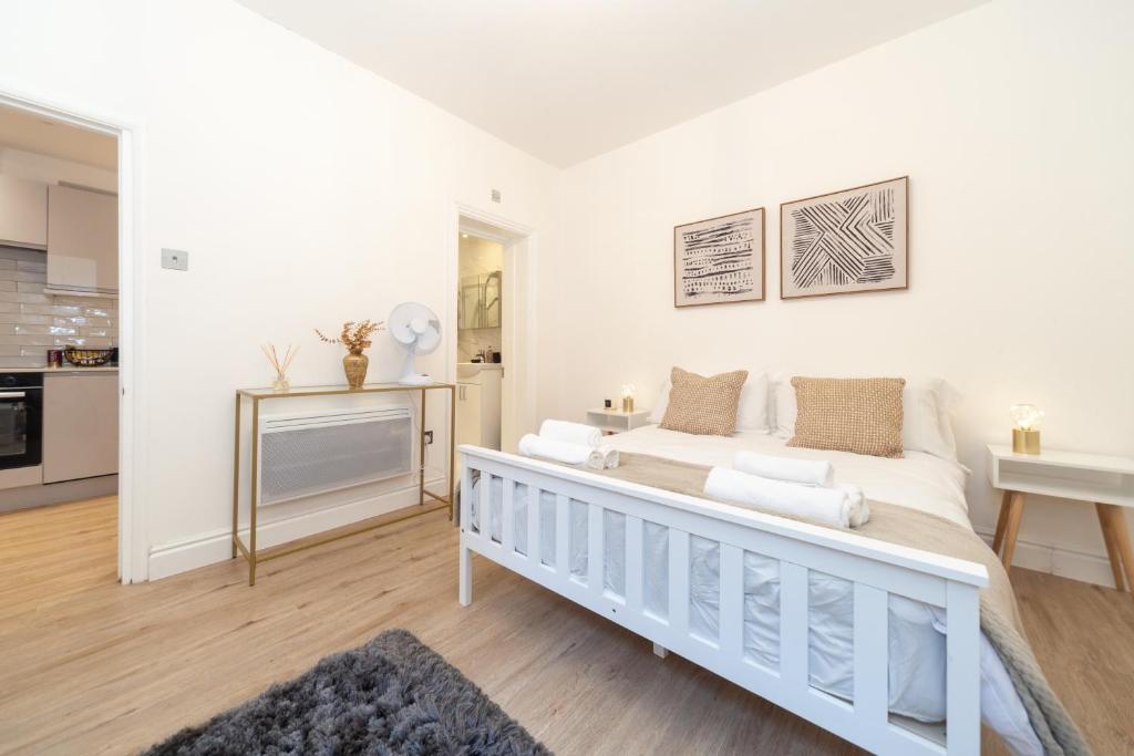 a white bedroom with a bed and a kitchen at Kensington luxury flat with patio in London