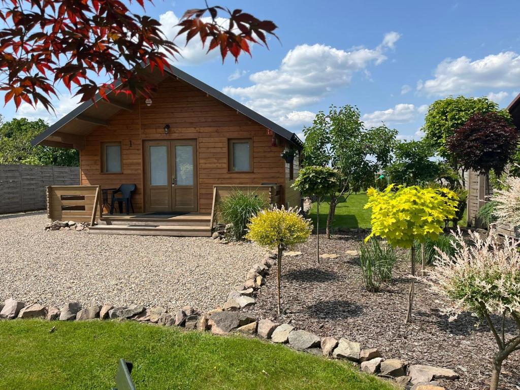 a small wooden house with a garden in front of it at Relax domki Zator in Zator