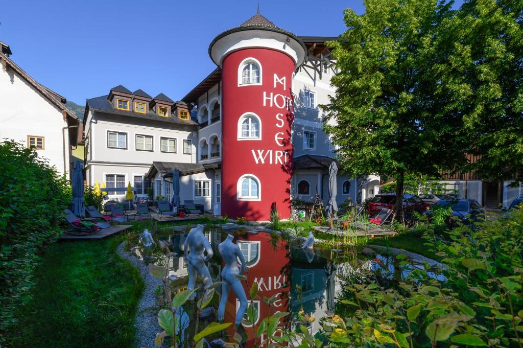 uma casa vermelha com um jardim em frente em Hotel Moserwirt em Bad Goisern