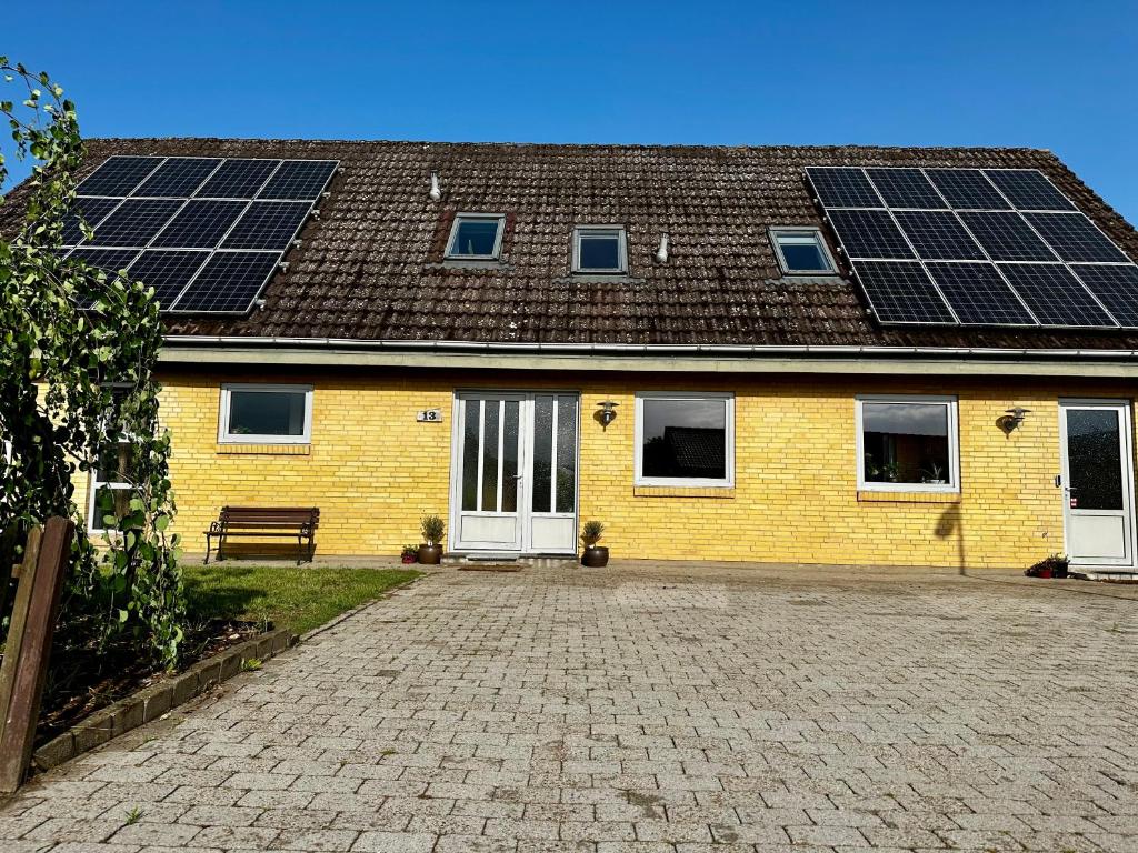 een geel huis met zonnepanelen op het dak bij OJ Home in Vojens