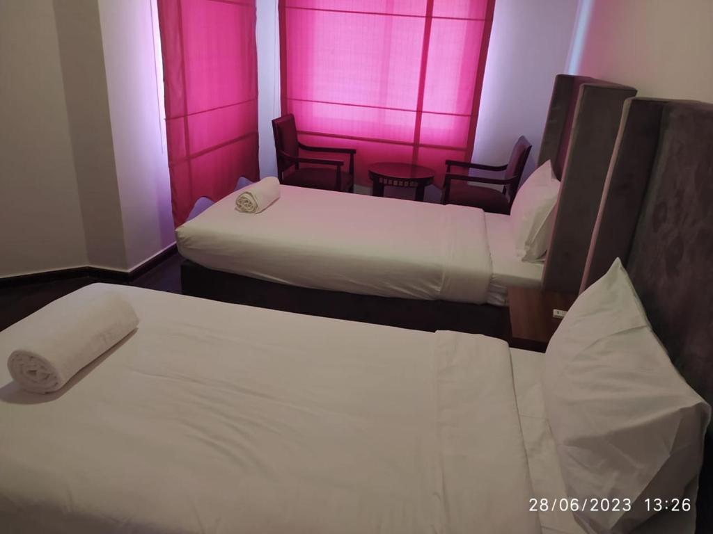 2 Betten in einem Hotelzimmer mit rosafarbener Beleuchtung in der Unterkunft Salalah Beach Villas in Salalah