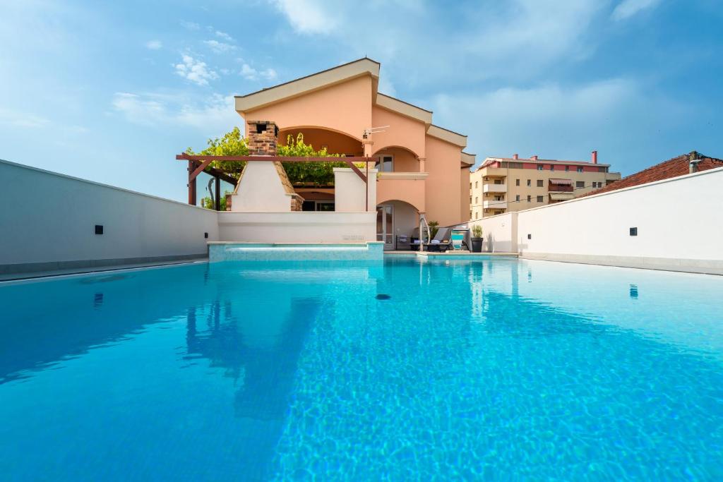 - une piscine d'eau bleue en face d'un bâtiment dans l'établissement Neretva Valley Apartments - Heated Pool, à Metković