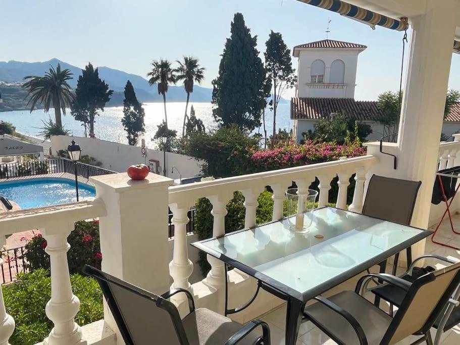 a balcony with a table and chairs and a swimming pool at Carabeillo Seaview Apartment in Nerja