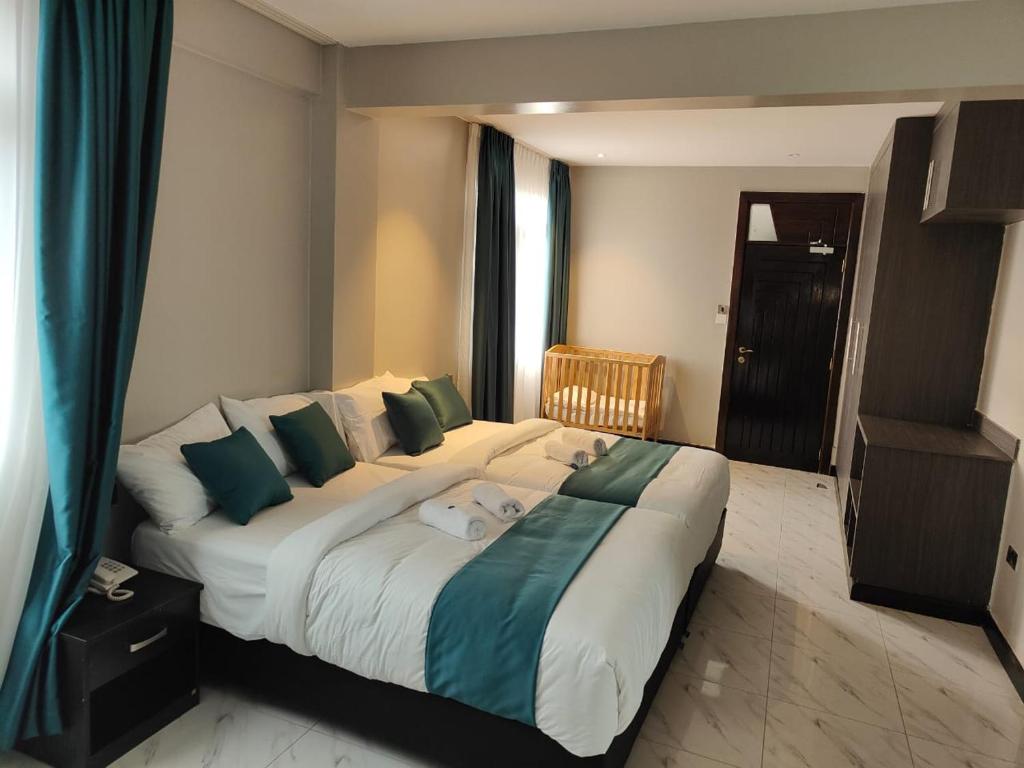 a bedroom with a large bed with green and white pillows at Hotel Lourdes, Siaya in Siaya