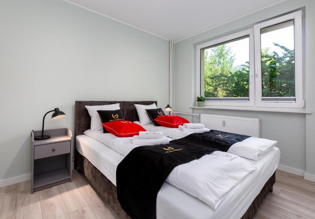 um quarto com 2 camas com almofadas vermelhas e uma janela em ApartamentyGdanskEU - Mieszkanie Mewa em Sopot