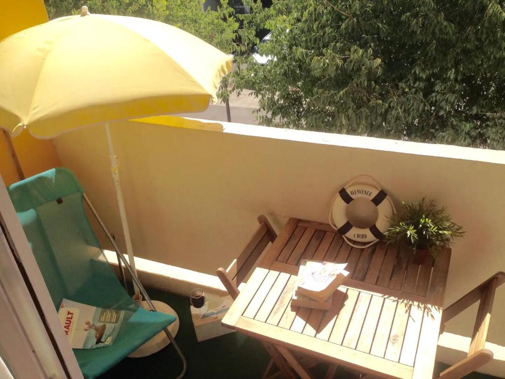 un balcon avec une table, une chaise et un parasol dans l'établissement Studio rénové + loggia 5 mn des thermes / c.ville - La Case à Jo, à Balaruc-les-Bains