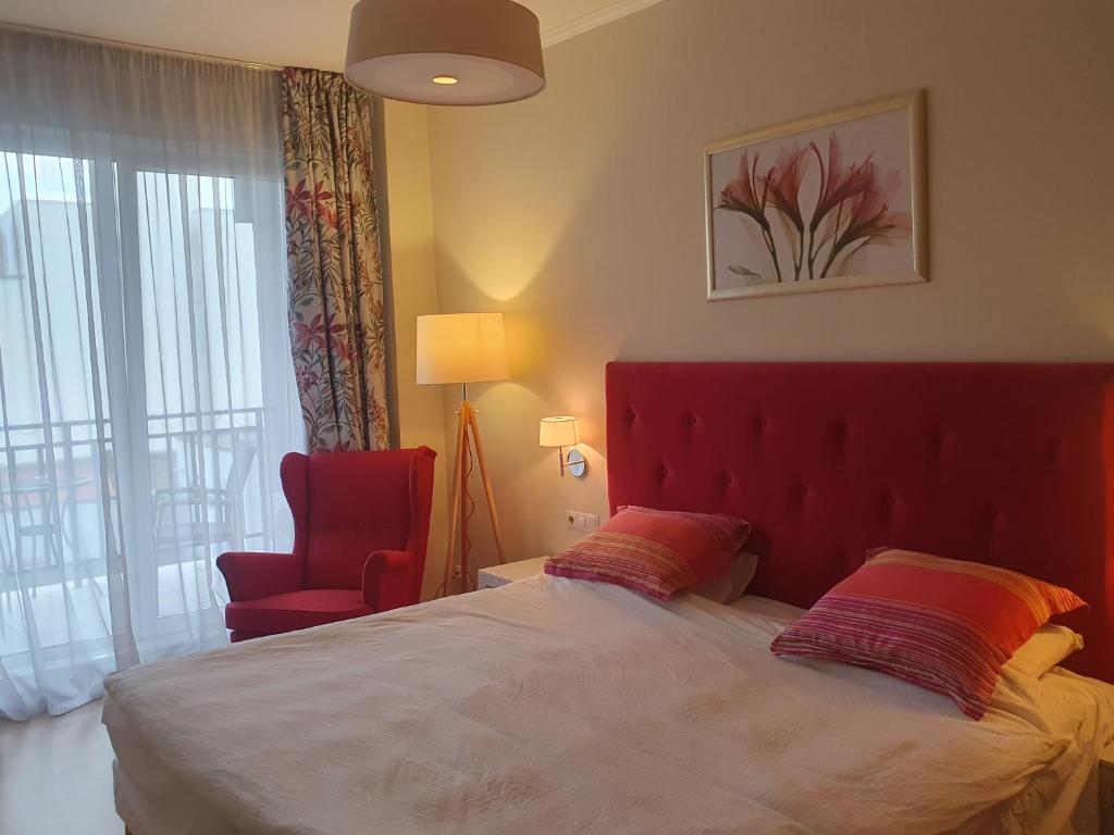 クルジュ・ナポカにあるTraian Residenceのベッドルーム1室(赤いヘッドボード付きのベッド1台、赤い椅子付)