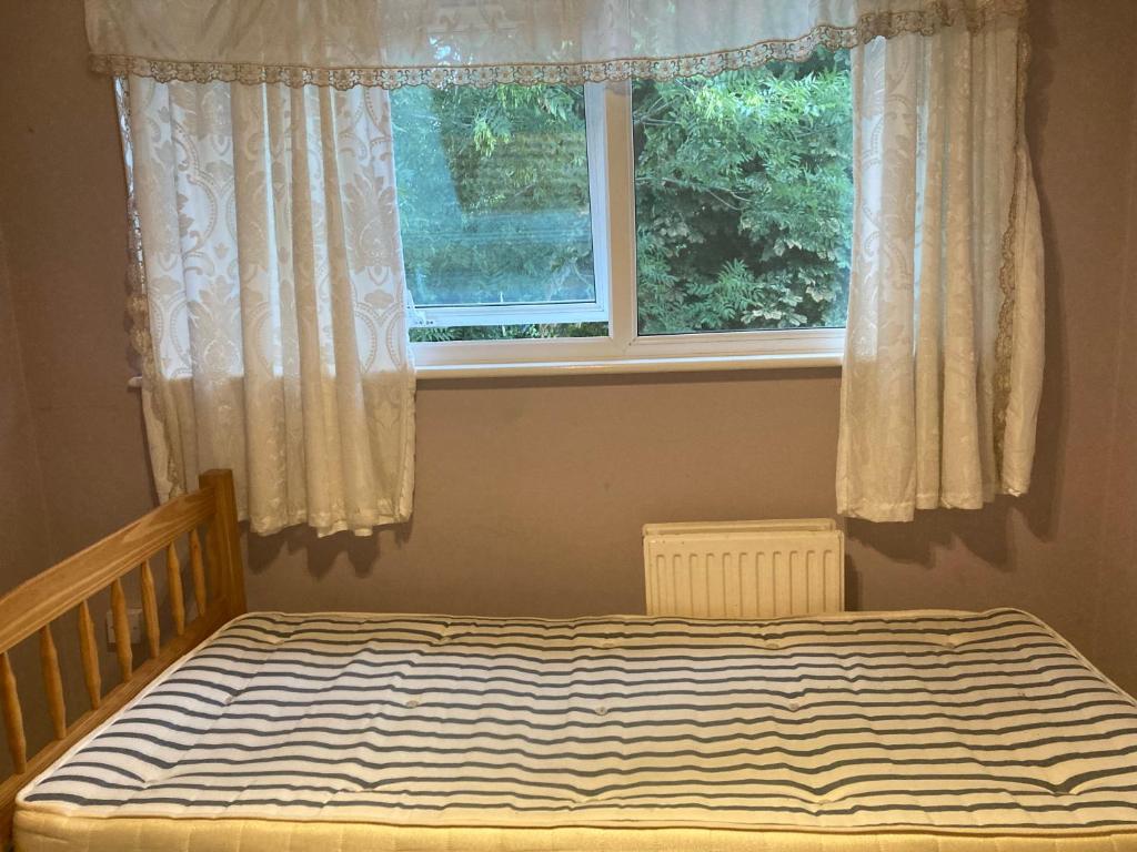 een bed in een slaapkamer met een raam bij C&C in Croydon