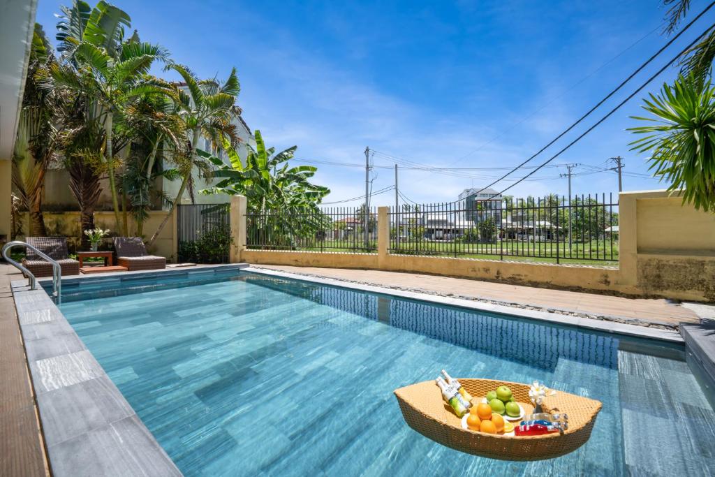 uma piscina com uma tigela de fruta numa cesta em Palm Boutique Village - STAY 24H em Hoi An