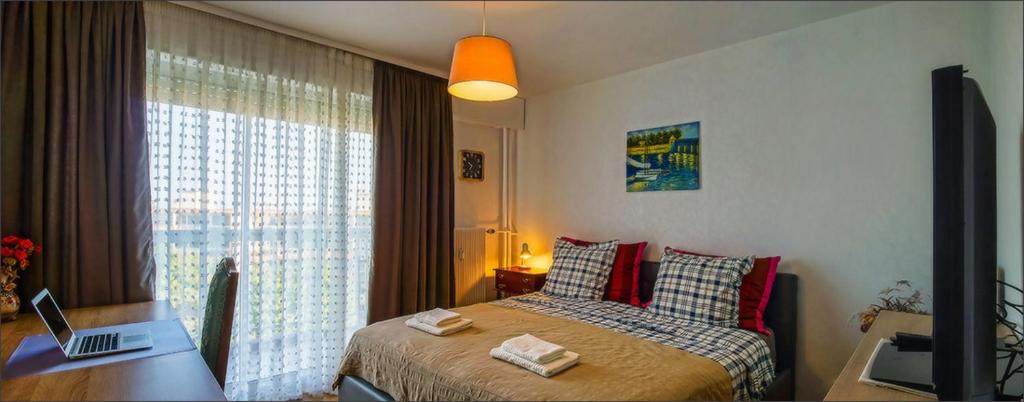 a bedroom with a bed with red pillows and a desk at Chambre chez Victor in Lingolsheim