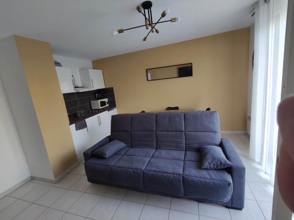 un canapé bleu dans un salon avec une cuisine dans l'établissement Agde Studio proche Plage, à Agde