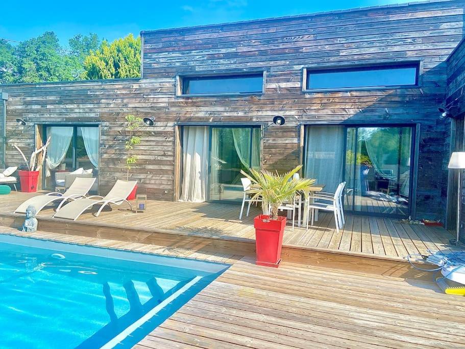 une maison avec une terrasse en bois et une piscine dans l'établissement Villa Bois Piscine Bordeaux, à Bonnetan