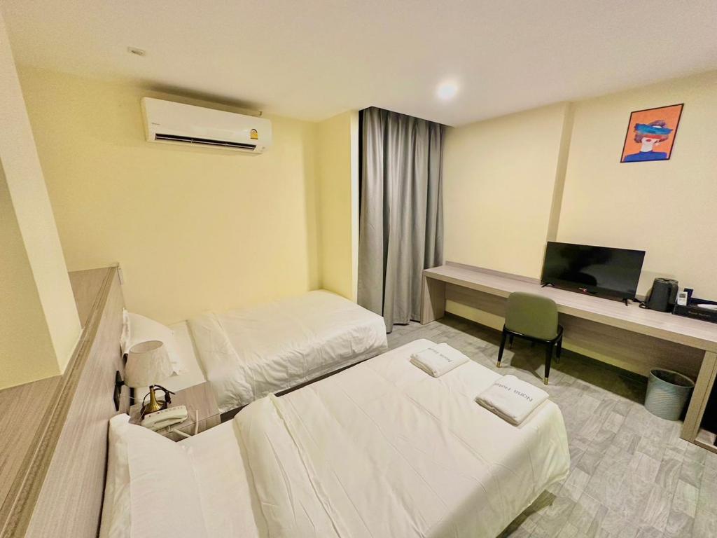 a hotel room with two beds and a desk at Nona Hotel, Bangkok in Makkasan