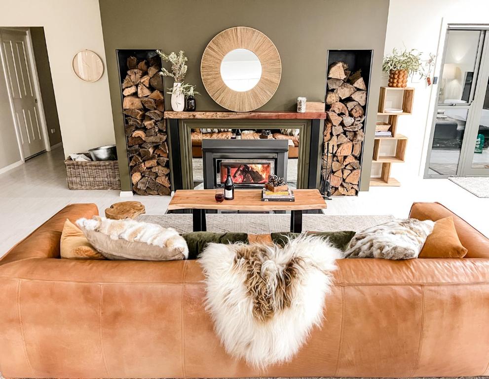 a living room with a brown couch and a fireplace at Hamilton House - Snowy Mountain Luxury Villas in Jindabyne