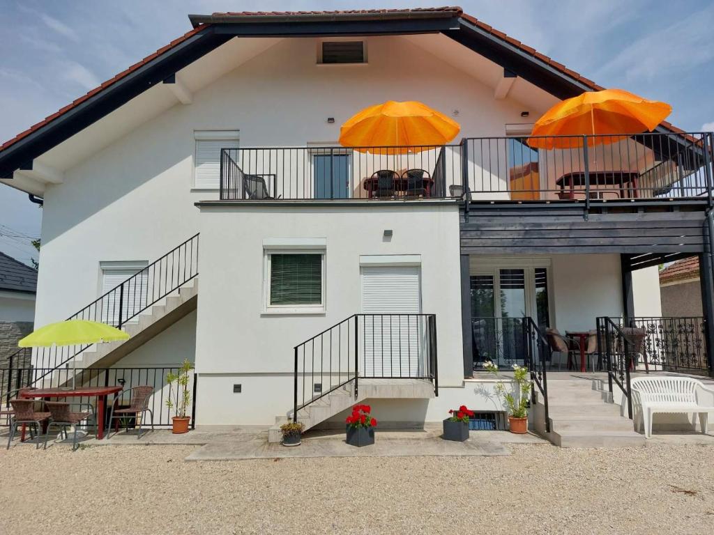 Casa blanca con 2 sombrillas naranjas en el balcón en Duna-Beach Apartman, en Kimle