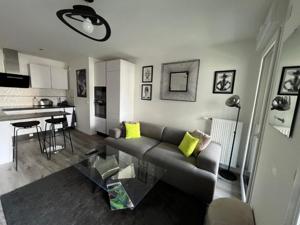 a living room with a couch and a kitchen at Appartement avec son jardin d’hiver in Poissy