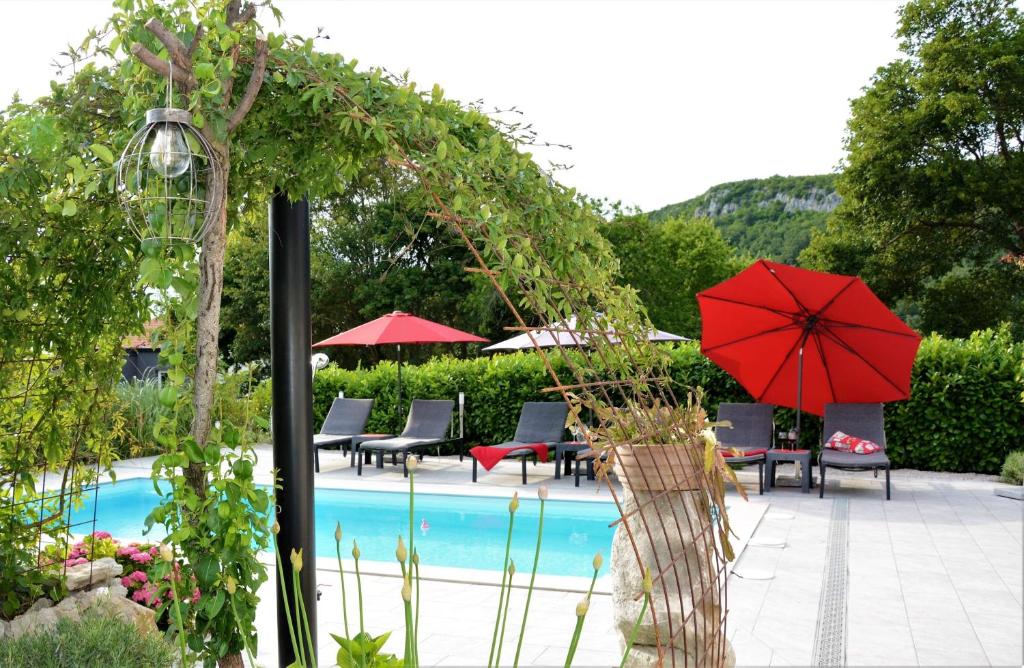 una piscina con sombrilla roja, mesas y sillas en Villa Anne A lovely place in the mountains, en Brest