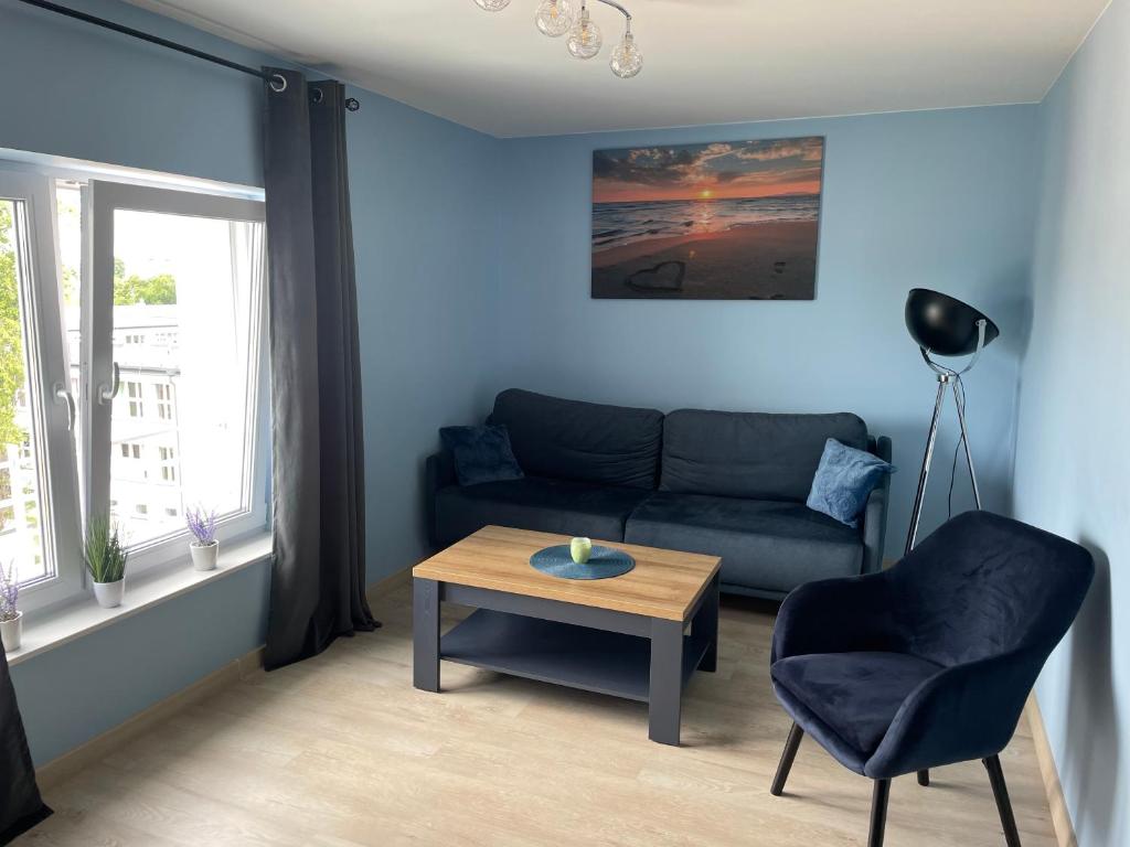 a living room with a couch and a table and a chair at Apartament Oksywie II in Gdynia