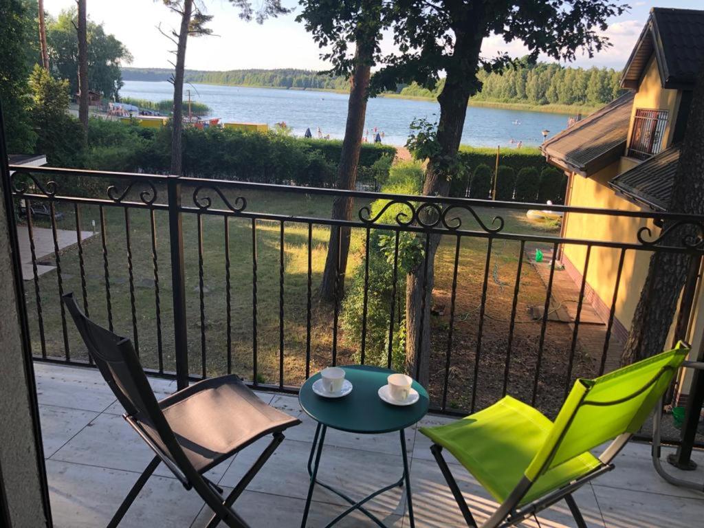 een tafel en stoelen op een balkon met uitzicht op een meer bij Luksusowy domek letniskowy z widokiem na jezioro, 8 osób Kamionki Małe in Kamionki Małe