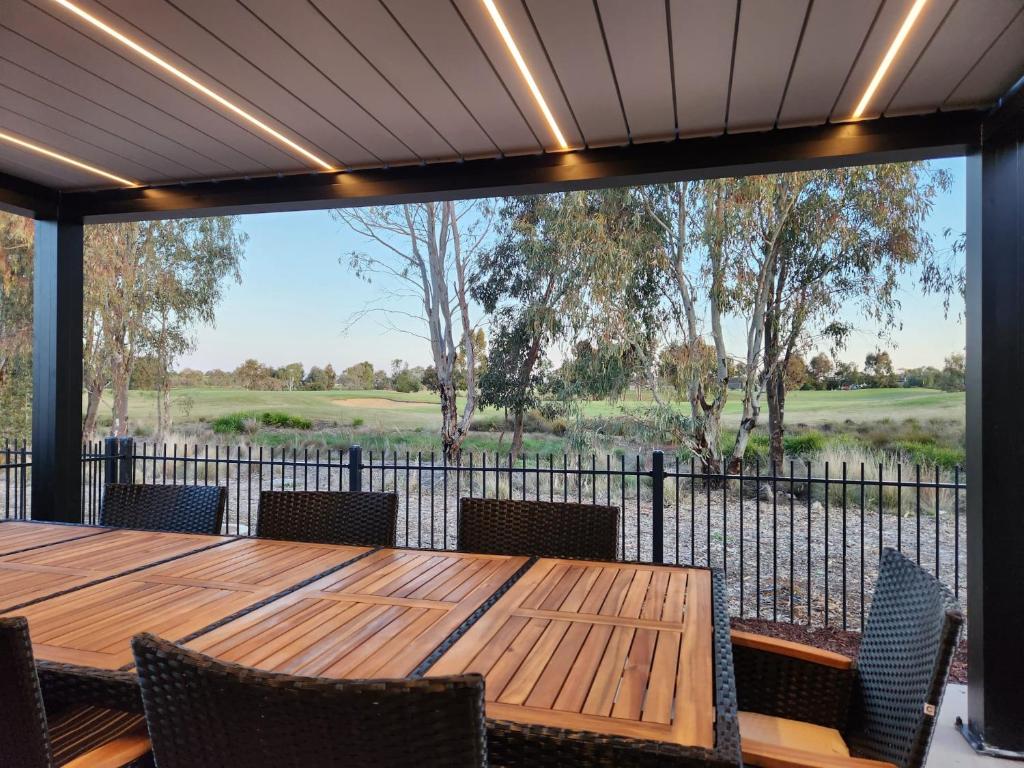 a patio with a table and chairs and a view of a golf course at Bullseye in Yarrawonga