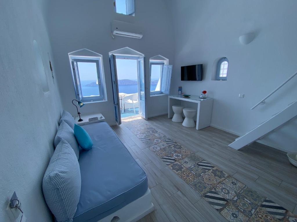 a living room with a blue couch and some windows at Heliades Apartments in Imerovigli