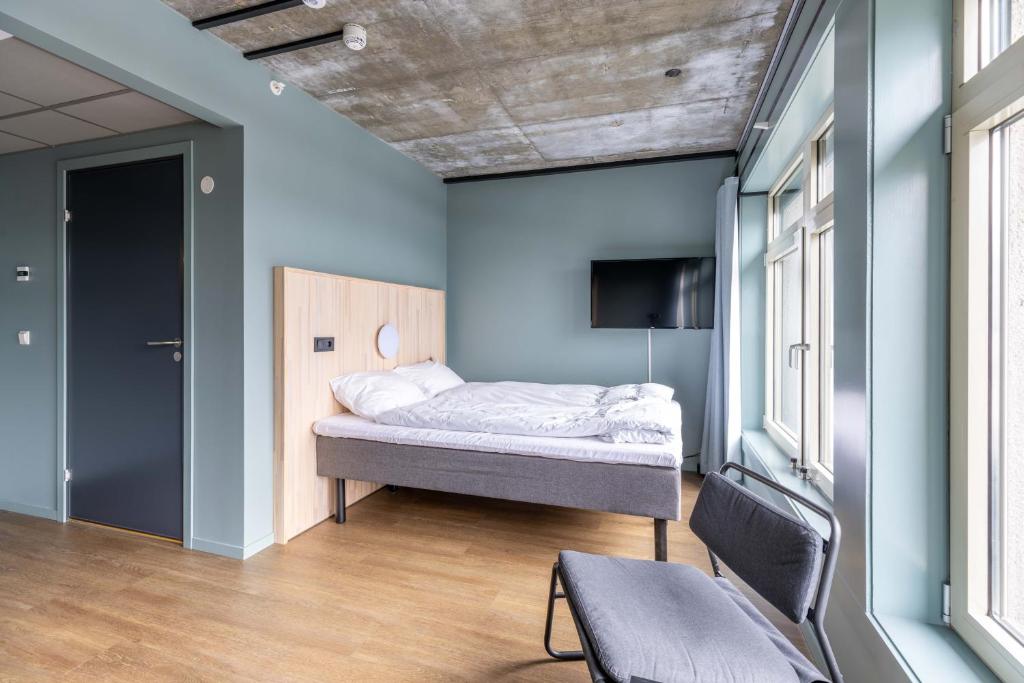 een slaapkamer met een bed in een kamer met blauwe muren bij Hotell Arendal in Arendal