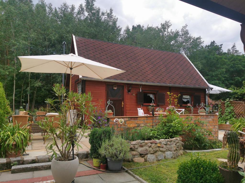 a small red house with an umbrella in the yard at Ferienhaus mit mediterraner Terrasse in Müllrose