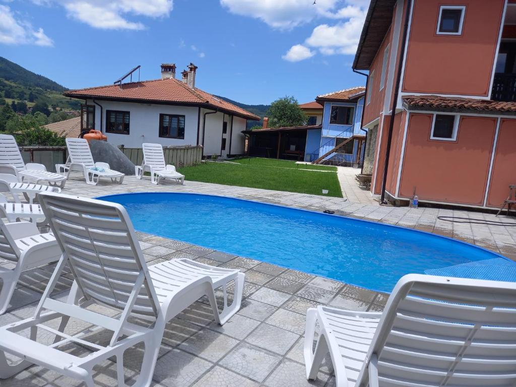 basen z białymi krzesłami obok domu w obiekcie Kъща за гости Демария w mieście Kopriwsztica